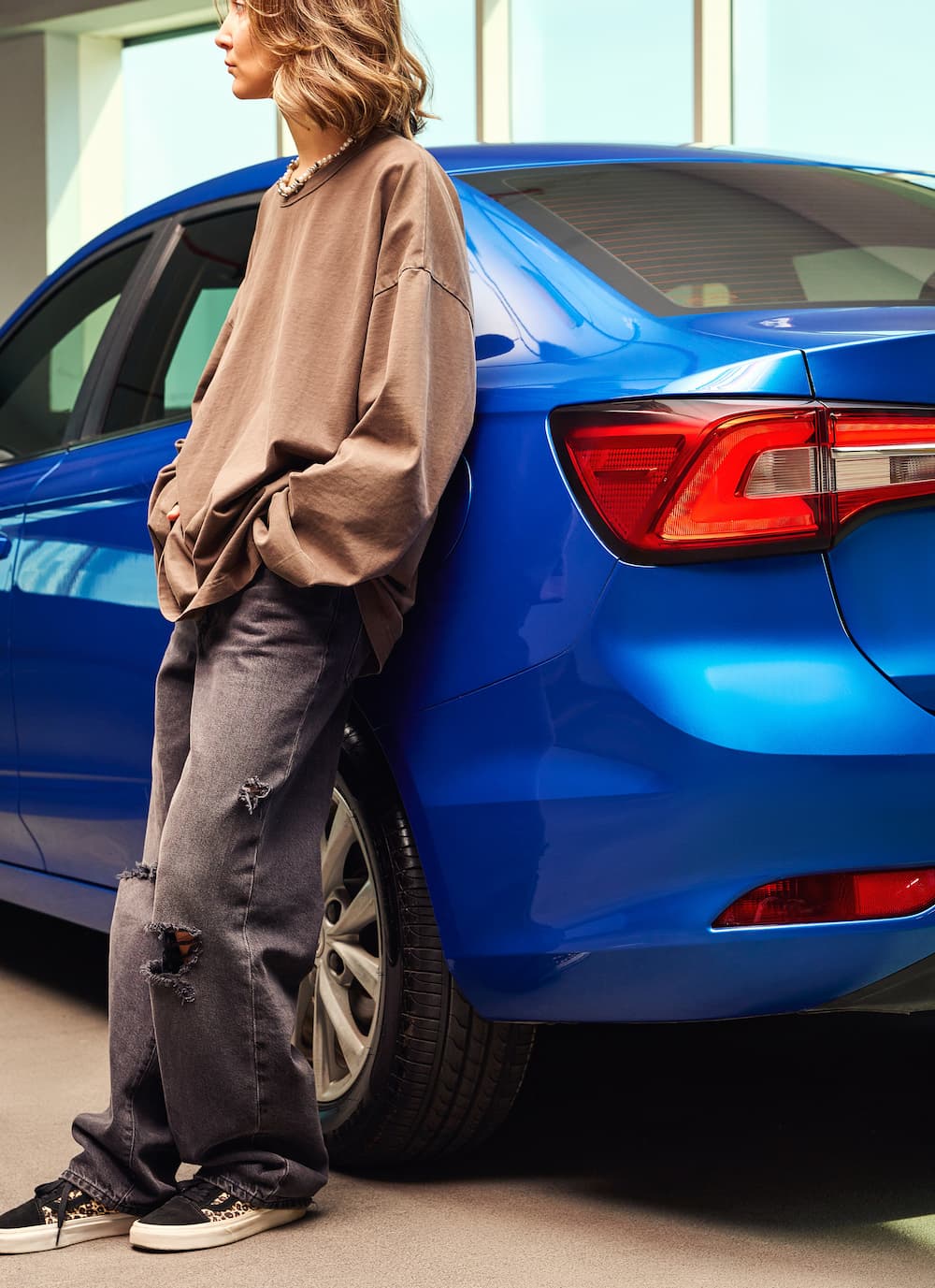 A woman leaning on a car