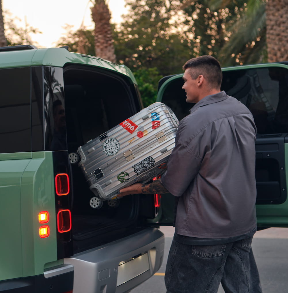 A man putting his suitcase in the car trunk