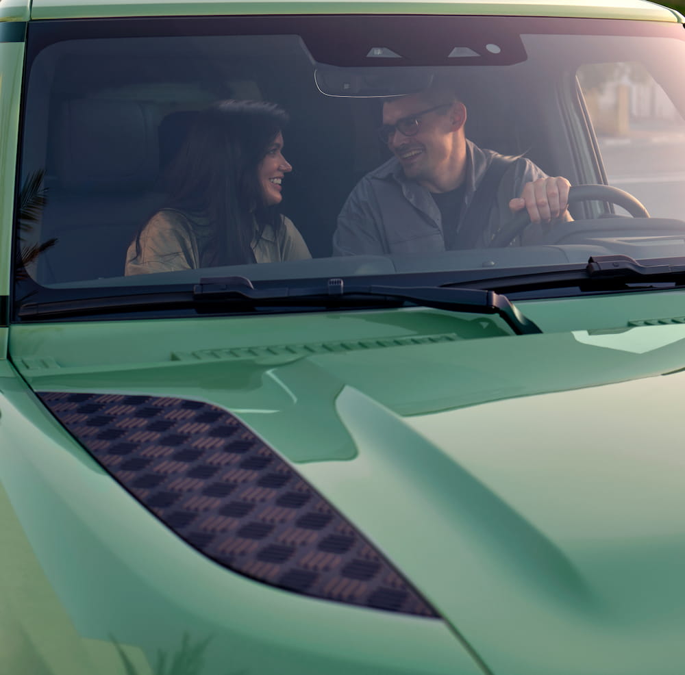 A man and a woman in a car, both happy