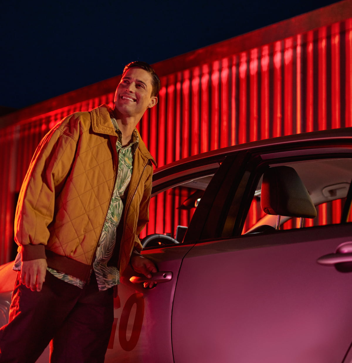 A happy man standing by a car