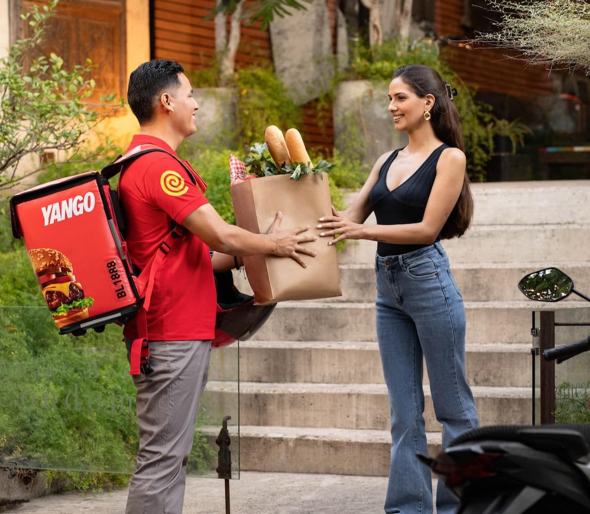 A man handing a bag of groceries to a woman